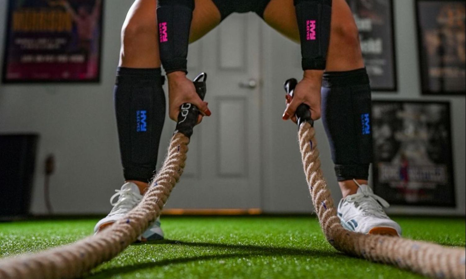 a woman in a gym holding a weighted rope while wearing ankle and wrist weights